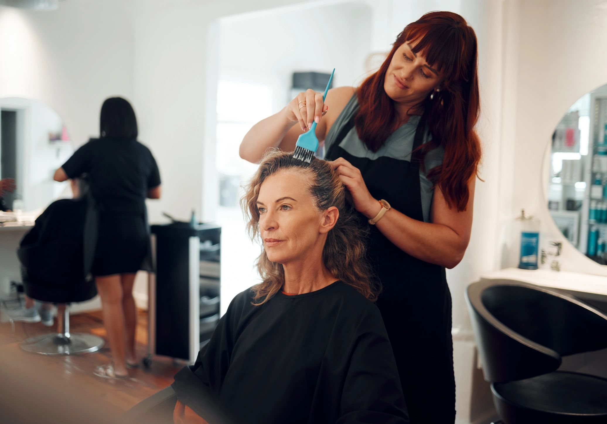 Hairdresser coloring and styling client’s hair