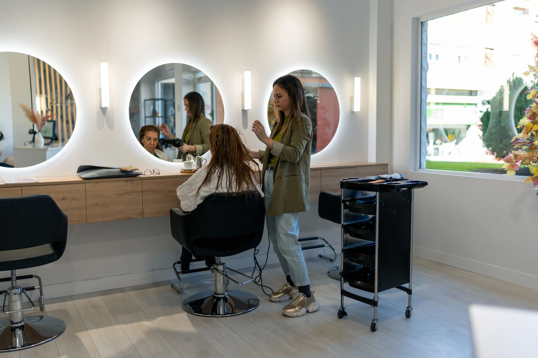 Focused stylist blow-drying client’s hair
