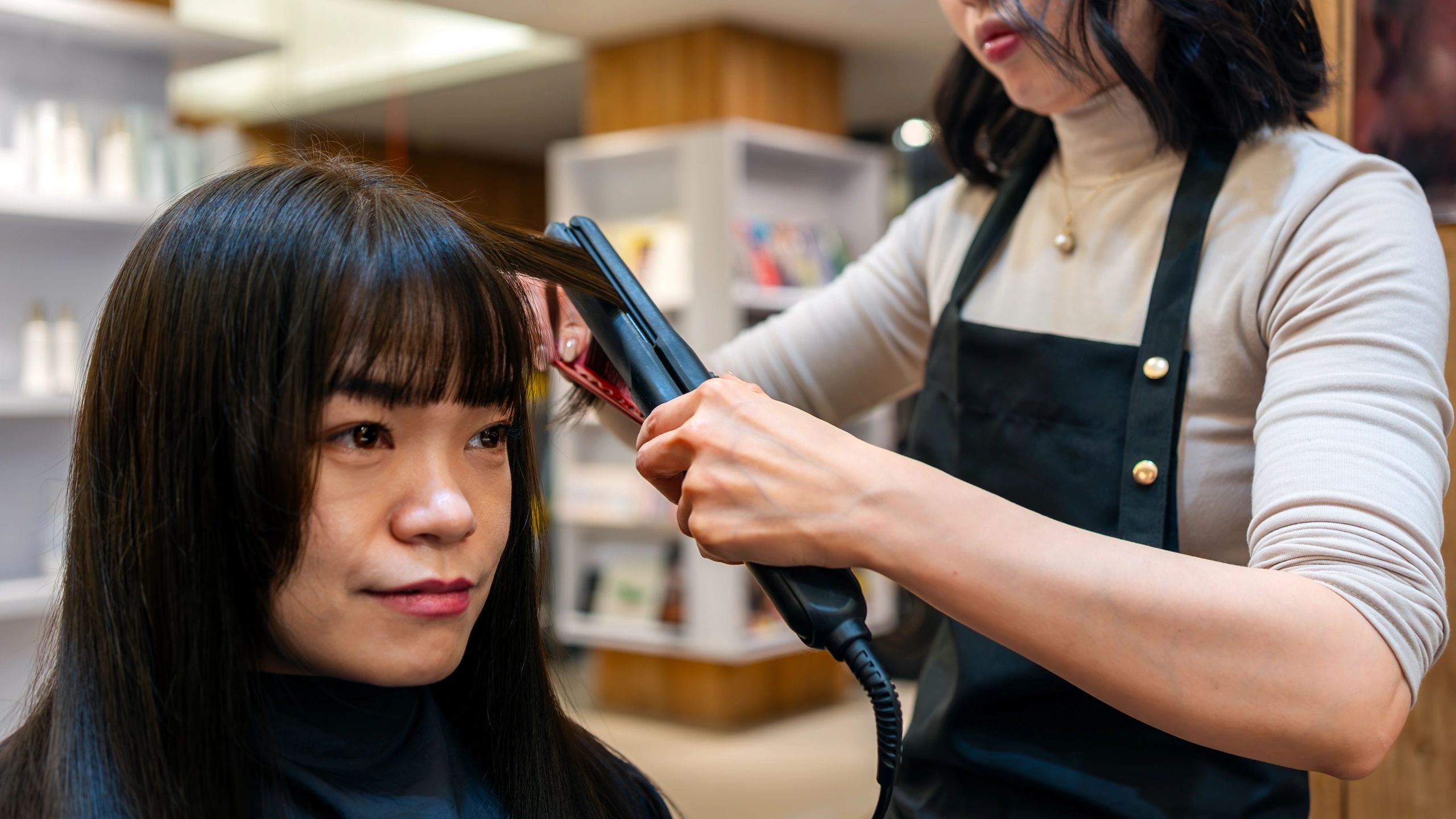 Stylist straightening client's hair